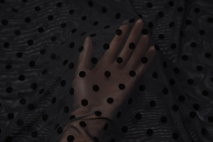 Gros plan sur un tissu en maille noire semi-transparente avec motif à pois classique