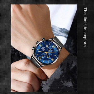 Close-up of men's business watch with blue dial and black mesh strap on wrist