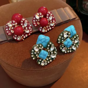 Vintage floral stud earrings set with rhinestones and turquoise accents on velvet