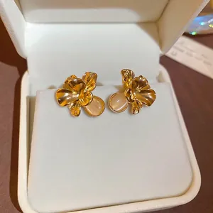 Elegant gold flower stud earrings with opal stone pendants on white velvet box