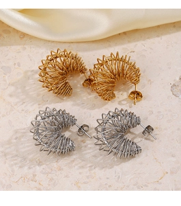 Macro detail of gold and silver spring-shaped C-style hoop earrings on silk