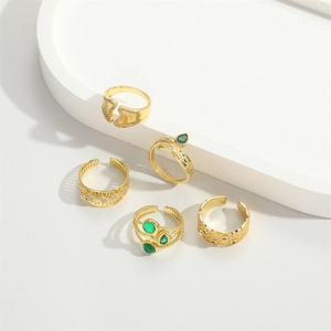 Minimalist gold ring set with green gemstones and zircon accents on white tray