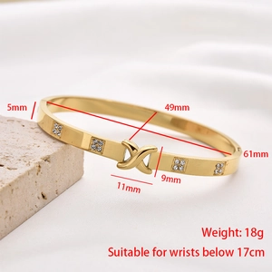 Detail view of gold stainless steel bangle with X-cross design and crystal accents