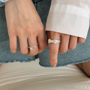 Close-up of 925 sterling silver bow ring and pearl ring worn with a casual outfit