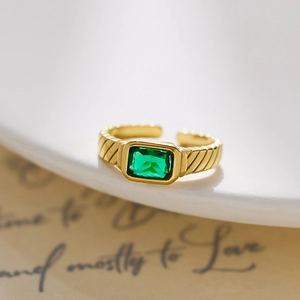 Close-up of 18k gold plated titanium ring with emerald-cut green cubic zirconia