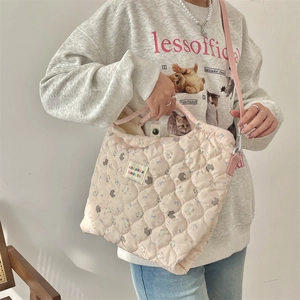 Close-up of pink quilted shoulder bag featuring cute cartoon bear print and label