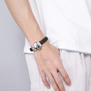 Close-up of black braided leather bracelet featuring a silver skull clasp on wrist