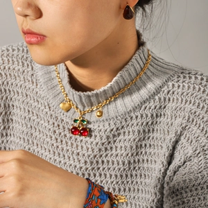 Golden cherry pendant necklace with heart and sun charms on a fine metal chain
