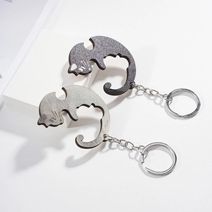 Detail of cat-shaped couple keychains in dark grey matte and light grey wood texture