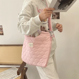 Détail du sac à bandoulière rose matelassé avec étiquette blanche et texture douce
