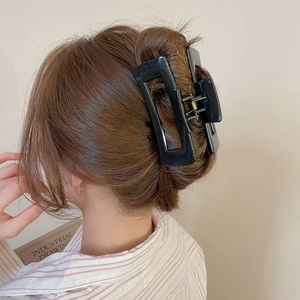 Close-up of a model wearing a large black square silicone hair claw clip for thick hair