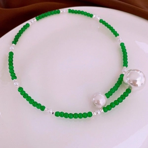 Detailed shot of green beaded necklace with silver metallic spheres on a white tray