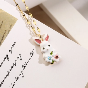 Macro detail of golden bunny necklace with enamel pendant and colored stones on card
