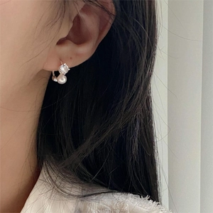 Close-up of 925 sterling silver earrings with zircons and pearls worn on a female model