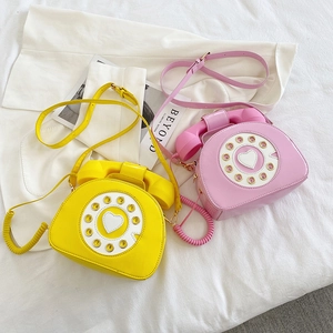 Detail of yellow and pink patent leather crossbody bags in retro rotary phone shape