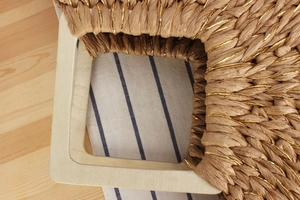 Detail of wooden handle and handwoven straw texture with elegant gold thread accents