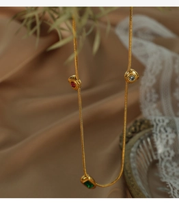 Detail of vintage gold necklace with green emerald-cut zircon and colorful round stones