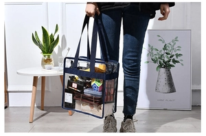 Deep blue trimmed transparent PVC beach bag shown by model in home setting