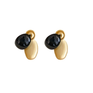 Minimalist gold metal disk and black oval bead earrings on a white background