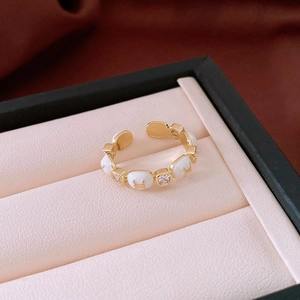 Close-up of gold-plated open ring with white enamel H charms and square zircons