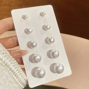 Detailed view of six pairs of round white pearl studs in varying sizes on display card
