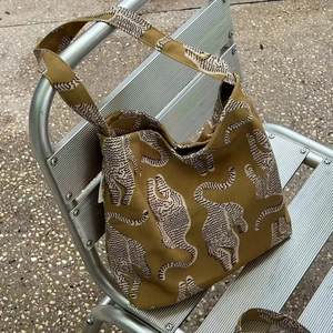 Détail d'un grand sac fourre-tout en coton léopard posé sur un banc en métal