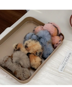 Close-up of colorful fluffy faux fur hair claws on a gold tray with a stylish aesthetic