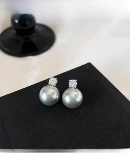 Detailed close-up of grey pearl earrings with sparkling diamond-cut zircon studs