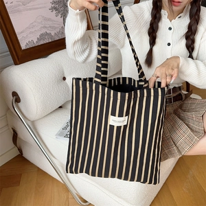 Detailed shot of striped canvas tote bag on white sofa showing texture and branding