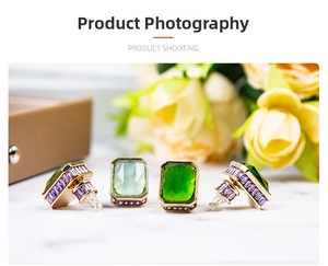 Close-up of vintage emerald-cut green stone earrings with purple zircon and gold plating