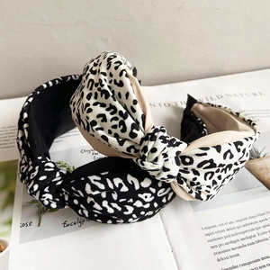 Detail of two leopard print knotted headbands in black and beige on an open book background