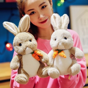 Cute plush rabbit toys in khaki and white colors holding small carrots in hands