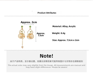 Detail view of asymmetric gold-tone gourd earrings with green beads and long chains