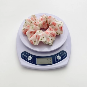 Detail showing pink floral chiffon scrunchie weight of 7.3g on a digital scale