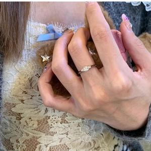 Detail shot of a silver braided rhinestone ring worn by a model on index finger
