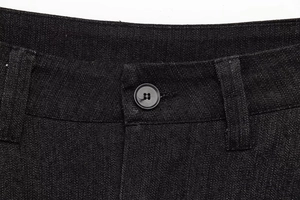 Dettaglio della vita in denim nero con chiusura a bottone e passanti per cintura