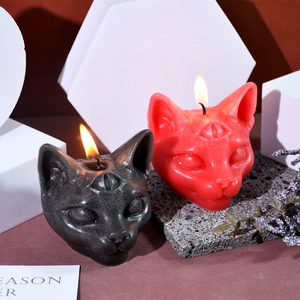 Macro view of three-eyed gothic cat head candles in black and red on stone