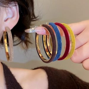Close-up of colorful velvet and gold hoop earrings shown on model and hand