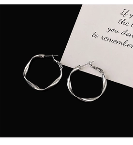 Detail shot of silver twisted hoop earrings with a high-polish metallic finish