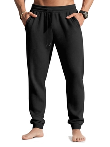 Detail of men's black waffle knit joggers with drawstring waist and ribbed cuffs
