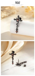 Macro shot of gothic snake-wrapped cross earring with red gemstones in gunmetal finish