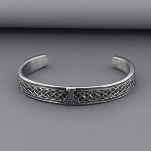 Close-up of vintage silver Thor's Hammer bracelet with Celtic knot patterns and Odin runes