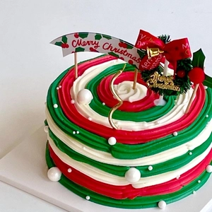 Close-up of Merry Christmas cake toppers on red and green frosting with a gold candle