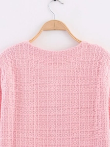 Detailed close-up of pink knit cardigan collar and shoulder texture on a wooden hanger