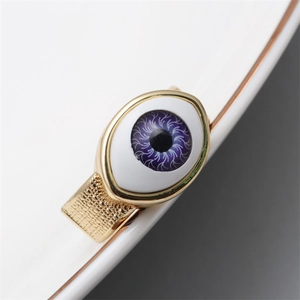 Detail of gold evil eye ring featuring purple zirconia and textured grid band