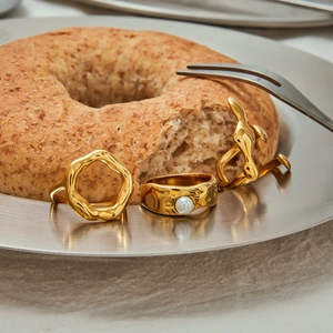Three irregular golden pearl rings displayed on a silver tray with bread props