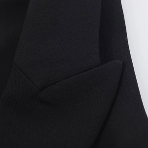 Gros plan du revers de blazer noir montrant la texture du tissu tissé et les coutures