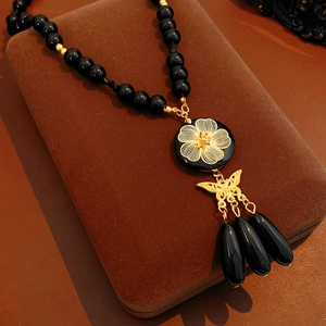 Detail of beaded necklace with gold flower, butterfly pendant and water drop tassels