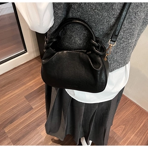 Détail du sac dumpling plissé noir avec poignée circulaire et garniture dorée chic