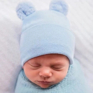 Close-up of light blue baby knitted hat with ear details and soft swaddle blanket set